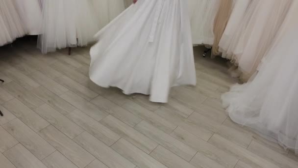Piękna dziewczyna mierzy suknię ślubną w salonie ślubnej. — Wideo stockowe