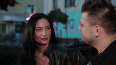 Mutlu adam ve kadın akşam el ele tutuşarak bir bankta sohbet.