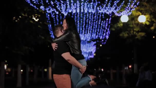 Beautiful man and woman are dancing in the evening on a city alley, a man takes a woman in his arms. — Stock Video