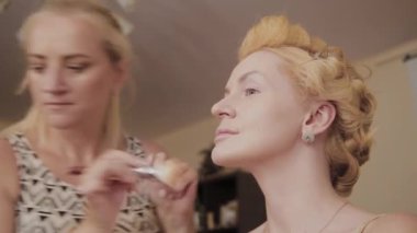 Profesyonel makyaj sanatçısı kadına model makyaj fotoğrafı uygular.