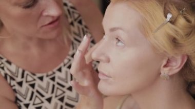 Profesyonel makyaj sanatçısı kadına model makyaj fotoğrafı uygular.