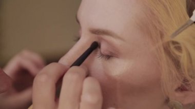 Profesyonel makyaj sanatçısı kadına model makyaj fotoğrafı uygular.