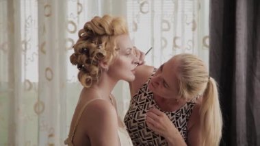 Profesyonel makyaj sanatçısı kadına model makyaj fotoğrafı uygular.