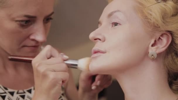 Professionell make-up artist applicerar make-up Foto av modell till kvinna. — Stockvideo