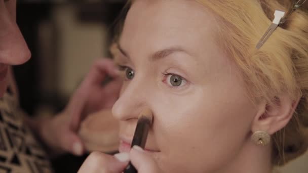 Professionell make-up artist applicerar make-up Foto av modell till kvinna. — Stockvideo