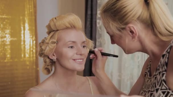 Professional make-up artist applies make-up photo of model to woman. — Stock Video