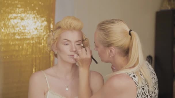 Professional make-up artist applies make-up photo of model to woman. — Stock Video