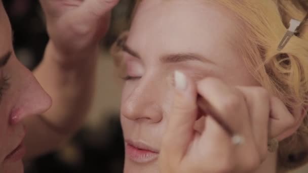 Professionell make-up artist applicerar make-up Foto av modell till kvinna. — Stockvideo