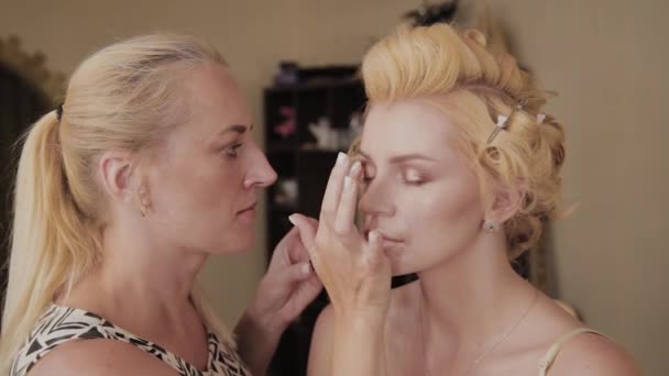 Professional make-up artist applies make-up photo of model to woman. — Stock Video