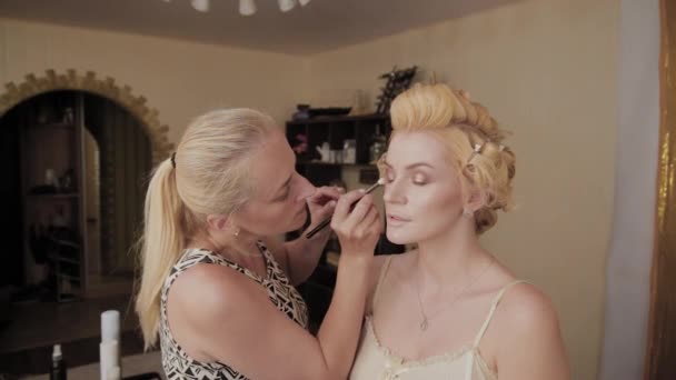 Professionell make-up artist applicerar make-up Foto av modell till kvinna. — Stockvideo