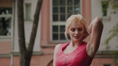 Kırmızı elbiseli fotoğraf modeli eski avluda yürüyor. Yakın çekim portre.