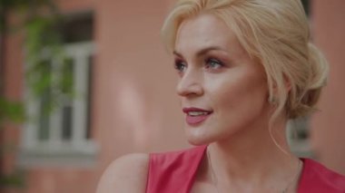 Kırmızı elbiseli fotoğraf modeli eski avluda yürüyor. Yakın çekim portre.