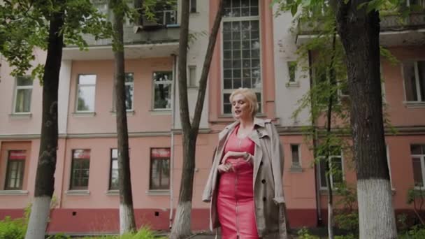Fotomodell i en röd klänning promenader på den gamla innergården. — Stockvideo