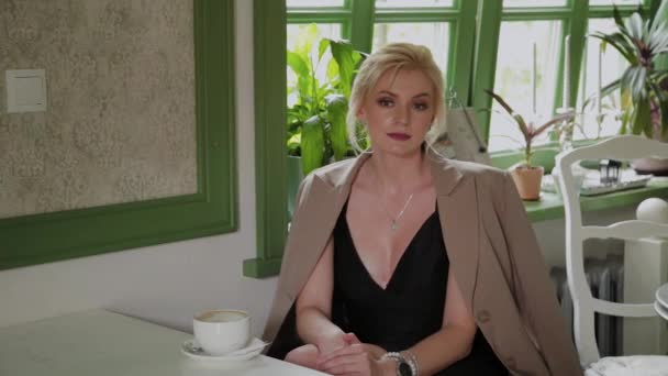 Hermosa mujer se sienta en un café y espera su orden . — Vídeos de Stock
