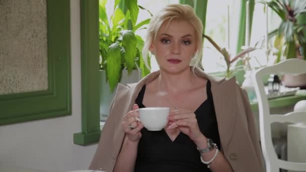 Όμορφη νεαρή επιχείρηση γυναίκα πίνει καφέ σε μια καφετέρια. — Αρχείο Βίντεο