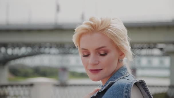 Beautiful young woman walks along the embankment by the river and enjoys what is happening. — Stock Video