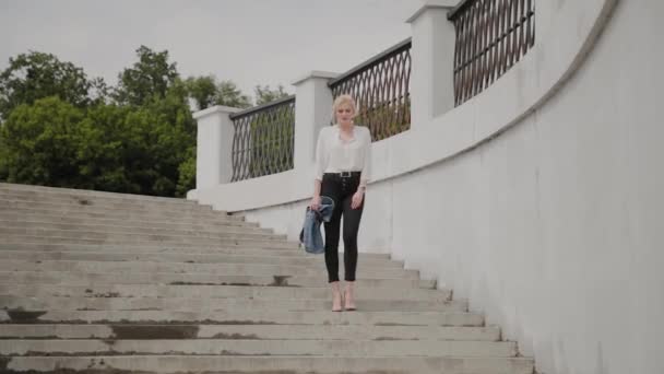 Mooie jonge vrouw loopt langs de dijk bij de rivier en geniet van wat er gebeurt. — Stockvideo