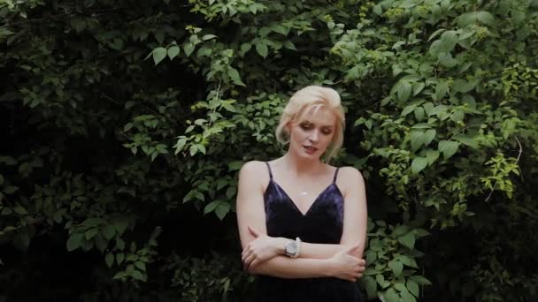 Όμορφη γυναίκα μοντέλο φωτογραφία στέκεται σε πράσινους θάμνους το καλοκαίρι. — Αρχείο Βίντεο