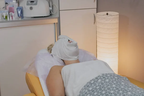 여자는 크림을 흡수하는 닫힌 얼굴과 미용실에서 소파에 누워. — 스톡 사진