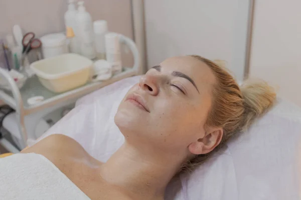 A woman lies on a couch waiting for a procedure in a beauty parlor.