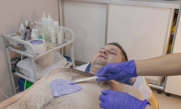 Homem bonito no procedimento de depilação em um salão de beleza . — Fotografia de Stock