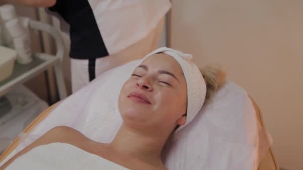Mulher bonita em roupão de banho deitado e esperando procedimento de cuidados faciais no salão de spa de luxo — Vídeo de Stock