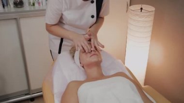 Kadın Spa salonunda yüz masajı yapıyor.