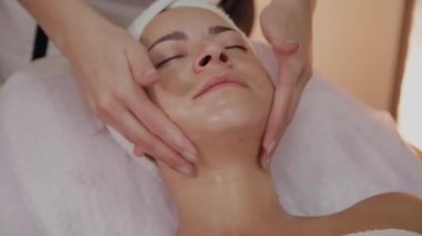 Kadın Spa salonunda yüz masajı yapıyor.