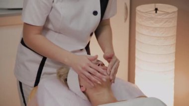 Kadın Spa salonunda yüz masajı yapıyor.