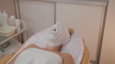 Yüzünde bir havlu ile güzellik uzmanında işlem kadın.