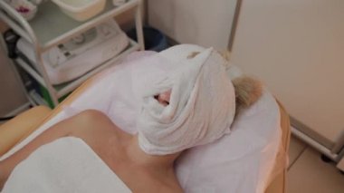 Yüzünde bir havlu ile güzellik uzmanında işlem kadın.