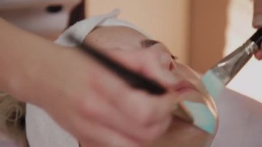 Profesyonel güzellik kadın yüzünde fırçalar ile maske uygulama.