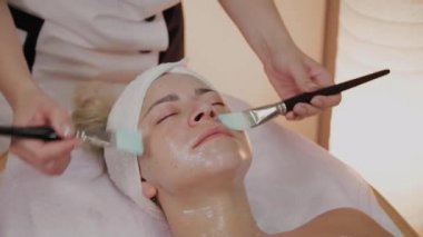 Profesyonel güzellik kadın yüzünde fırçalar ile maske uygulama.