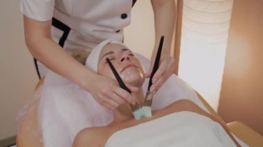 Profesyonel güzellik kadın yüzünde fırçalar ile maske uygulama.