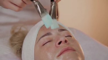 Profesyonel güzellik kadın yüzünde fırçalar ile maske uygulama.