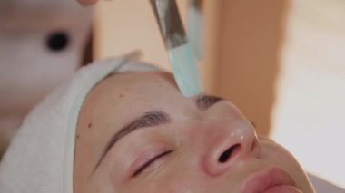 Profesyonel güzellik kadın yüzünde fırçalar ile maske uygulama.