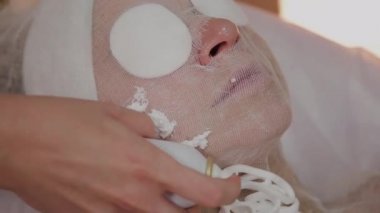 Profesyonel güzellik yüz bir köpük maskesi uygular.