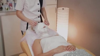 Profesyonel güzellik bir kadın yüzünde bir maske kaldırır.