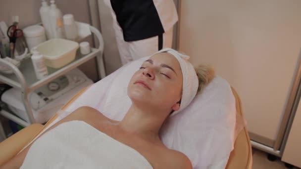 Bella giovane donna in accappatoio sdraiato e in attesa procedura di cura del viso al salone di lusso spa — Video Stock