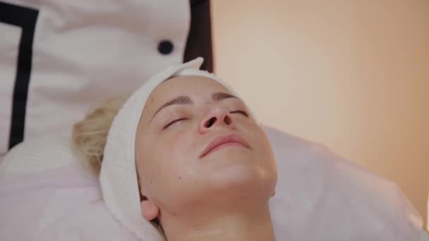 Woman on the procedure at the beautician with a towel on her face. — Stock Video