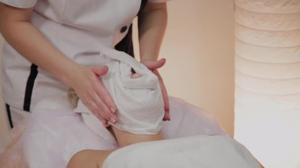 Vrouw op de procedure bij de schoonheidsspecialiste met een handdoek op haar gezicht. — Stockvideo