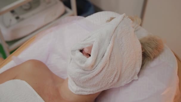 Kvinna på förfarandet på kosmetolog med en handduk på hennes ansikte. — Stockvideo