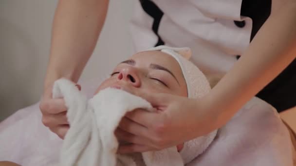 A professional beautician removes a towel from a womans face and wipes it. — Stock Video