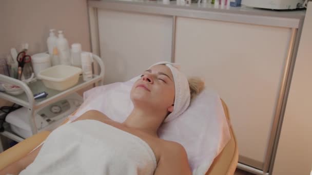 Hermosa mujer joven en albornoz acostada y esperando procedimiento de cuidado facial en el salón de spa de lujo — Vídeos de Stock