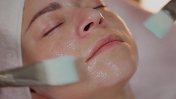 Esteticista profesional aplicando máscara con cepillos en la cara de la mujer . — Vídeos de Stock