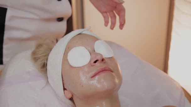 Επαγγελματική αισθητικός προετοιμάζει το πρόσωπο για την εφαρμογή μάσκα. — Αρχείο Βίντεο