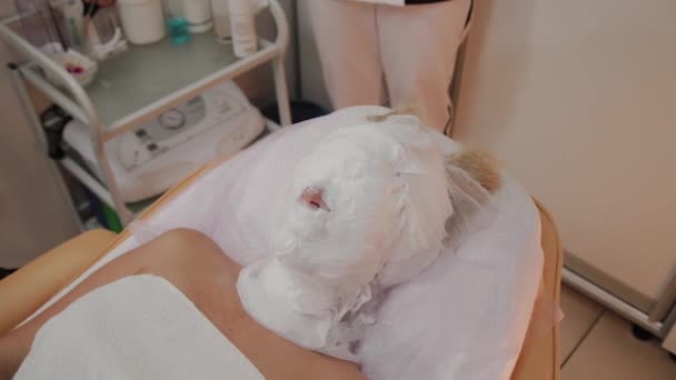 Cosmetische procedure. Vrouw in schoonheidssalon met masker op haar gezicht. Gezichtsmasker toepassing. — Stockvideo