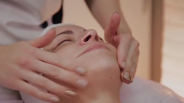 Schoonheidsspecialiste past crème op vrouw gezicht. — Stockvideo