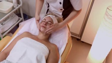 Kadın Spa salonunda yüz masajı yapıyor.