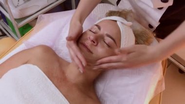 Kadın Spa salonunda yüz masajı yapıyor.